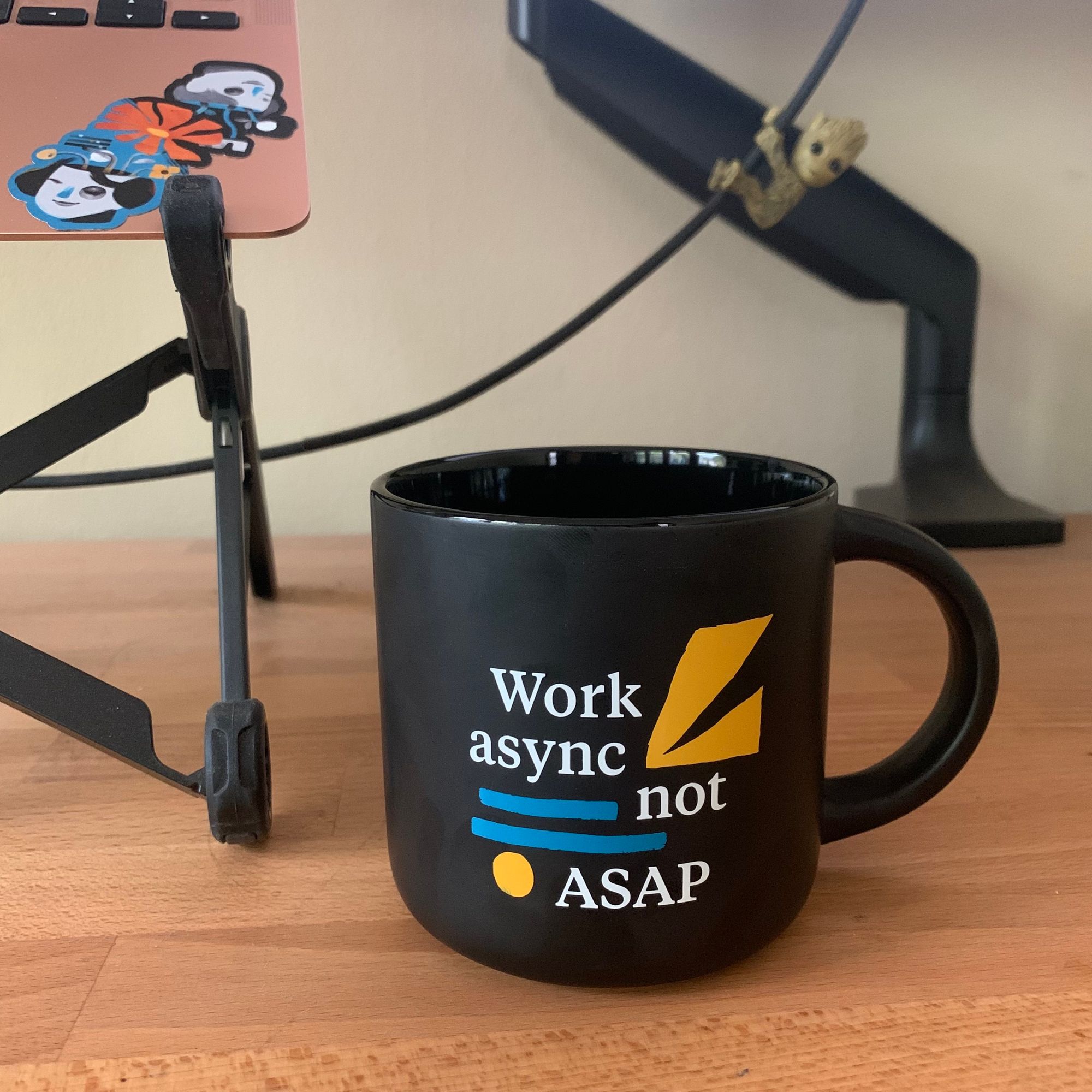 A matte black mug with "Work async not ASAP" in white lettering.